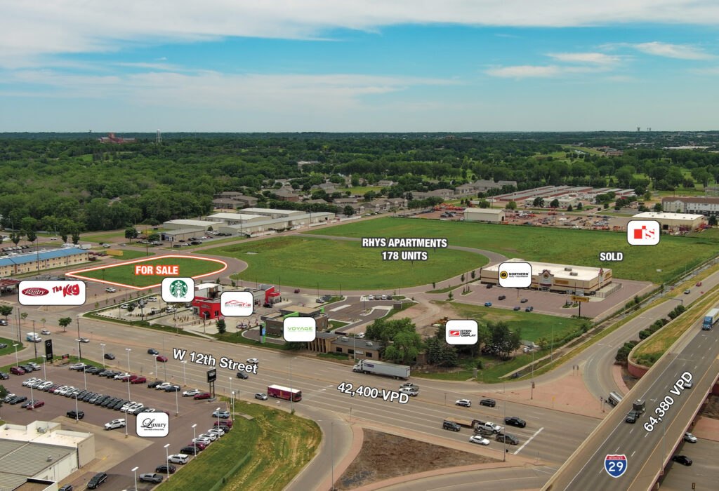Aerial of the Crossroads Development land for sale outlined at W 12th Street and Interstate 29, with the 178-unit Rhys Apartments site and adjacent sold parcel labeled