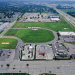 South view aerial of the available parcel at the Crossroads Development, with W. 12th Street retail in the foreground and the I-29 corridor beyond