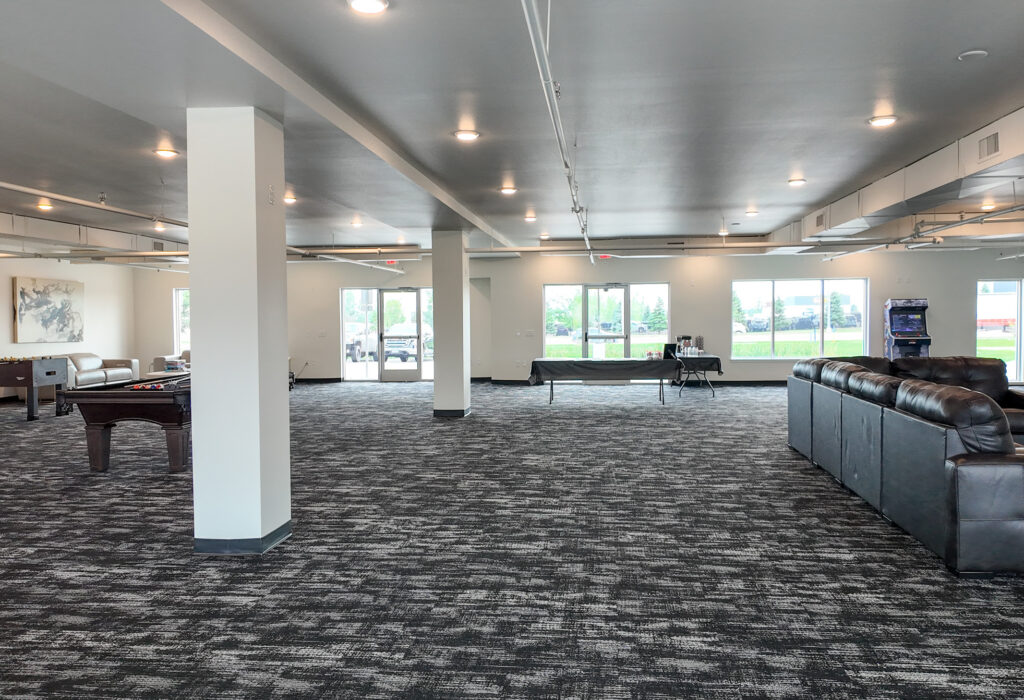 Wide interior view of finished commercial space with open floor area, columns and natural light
