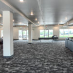 Wide interior view of finished commercial space with open floor area, columns and natural light