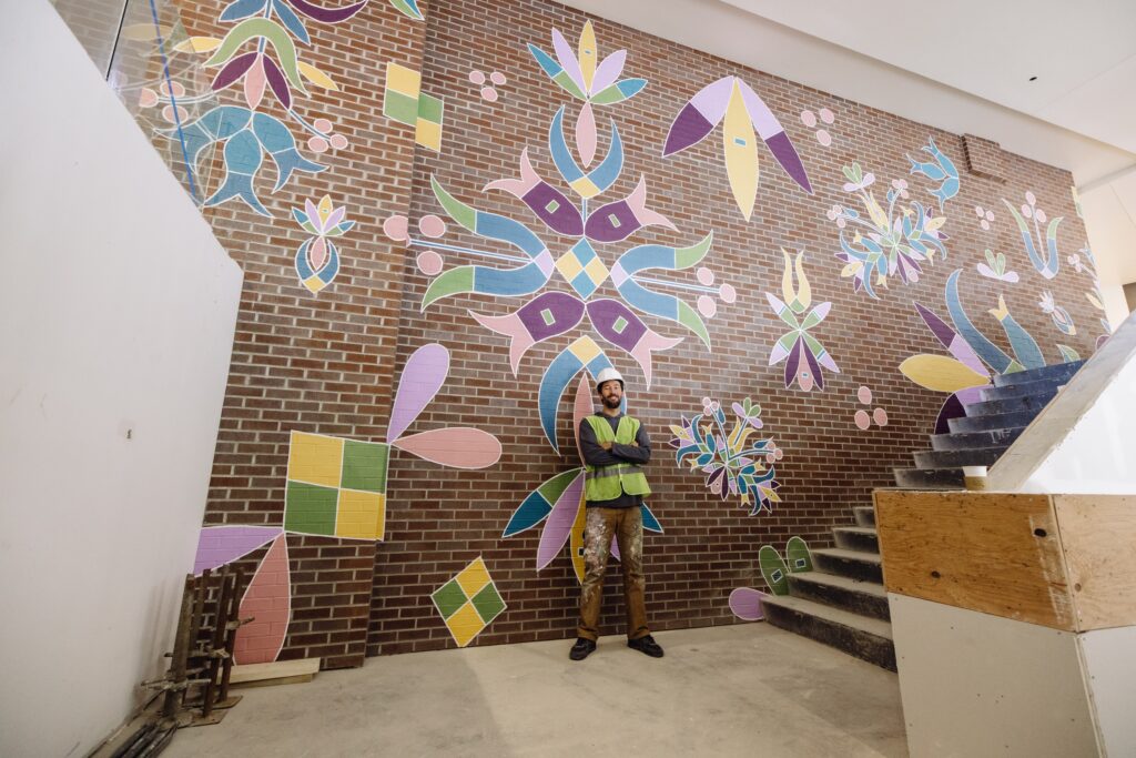 Taylor Gallegos in front of Canopy by Hilton Sioux Falls Downtown Mural