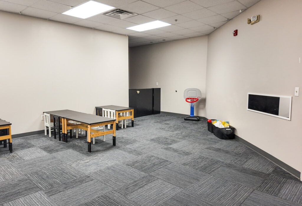Carpeted flexible-use room with tables and wall-mounted screen