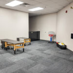 Carpeted flexible-use room with tables and wall-mounted screen