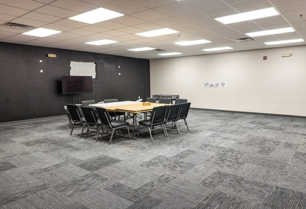 Large meeting room with conference tables and wall-mounted television