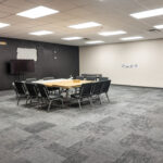 Large meeting room with conference tables and wall-mounted television