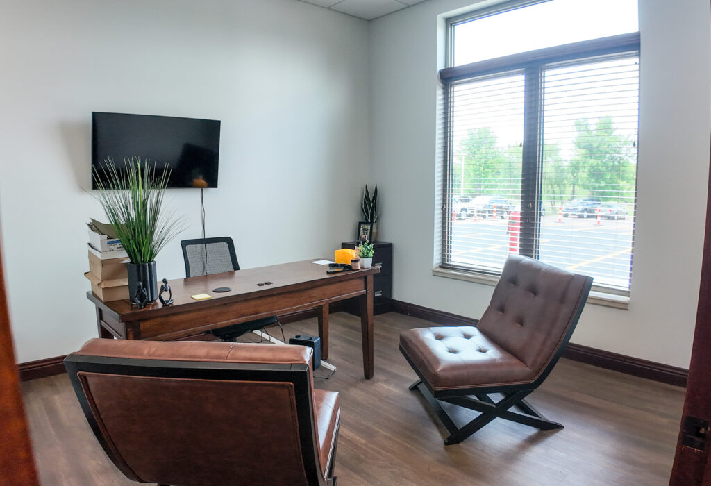 Windowed private office with desk and guest seating