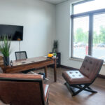 Windowed private office with desk and guest seating