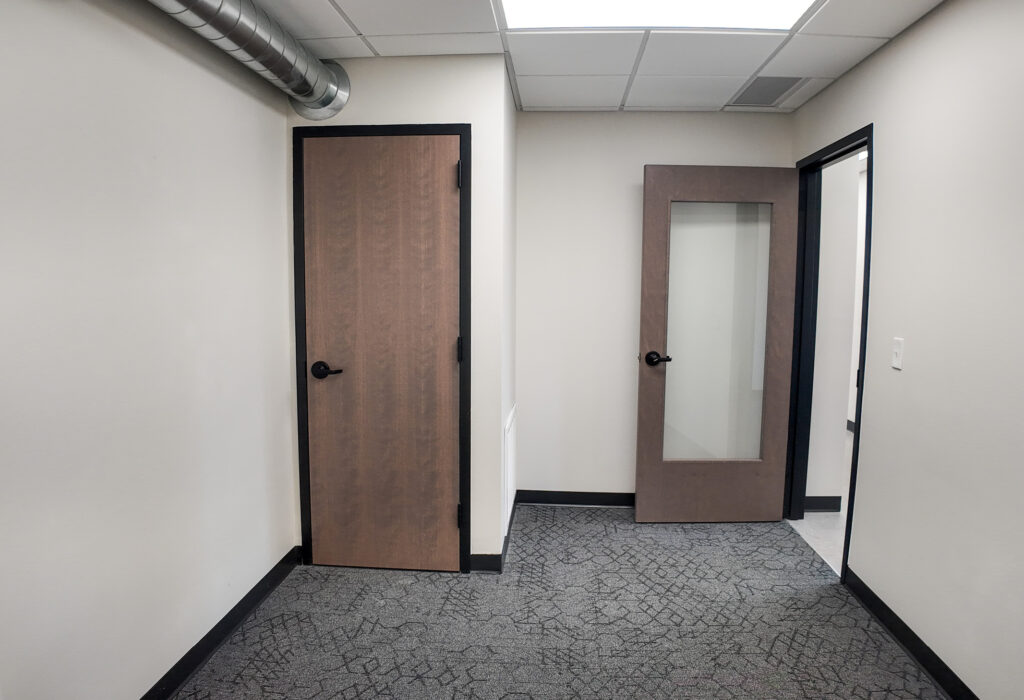 Carpeted office area with glass-panel door and exposed ductwork