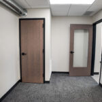 Carpeted office area with glass-panel door and exposed ductwork