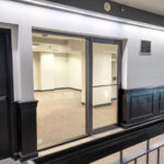 Common-area corridor leading to the glass suite entrance on the second level